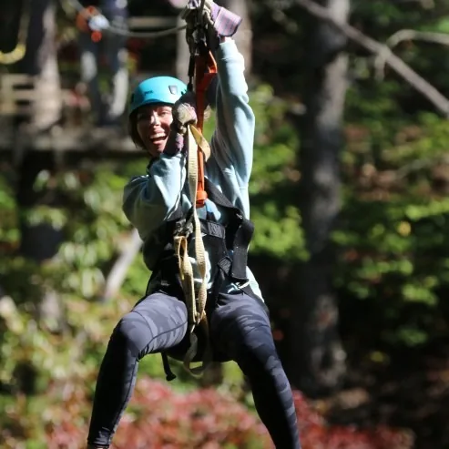A guest grinning mid-flight on the Ocoee zipline canopy tour